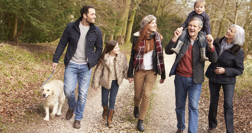 Multi-generational family walking with their dog in the fall