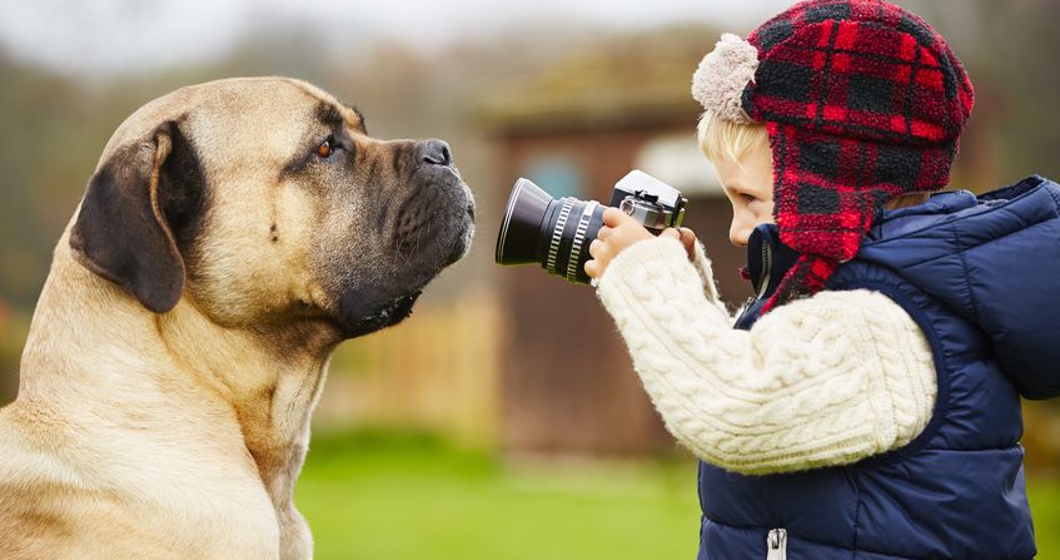 little boy with camera is shooting his dog