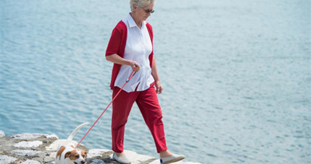 Woman walking her dog by the ocean
